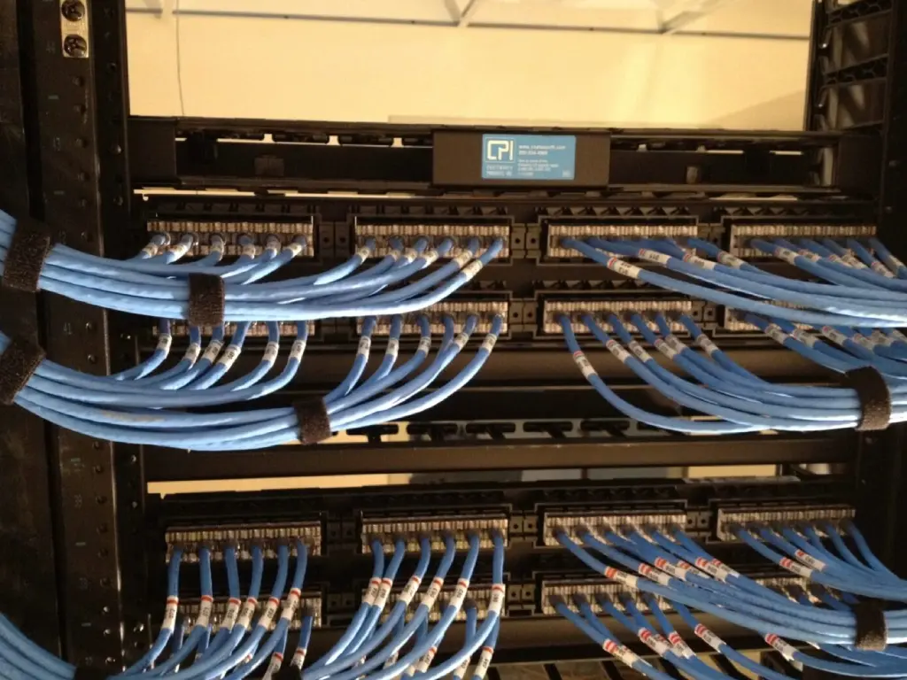 A bunch of wires hanging on the side of a rack.