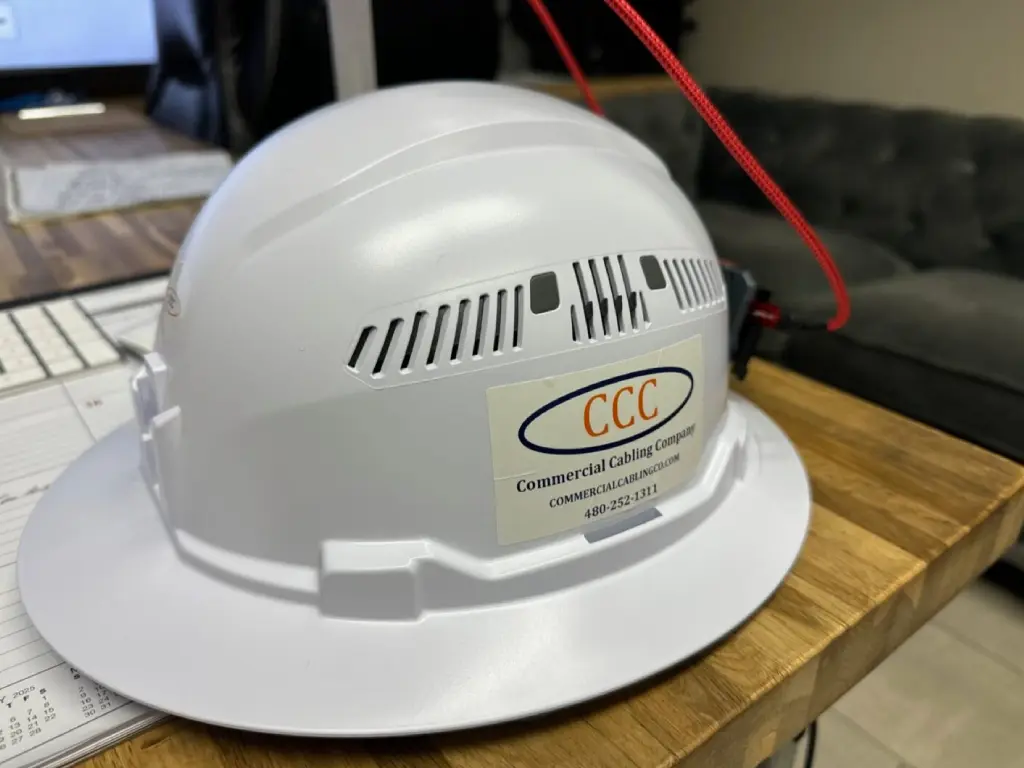 A white hard hat sitting on top of a wooden table.