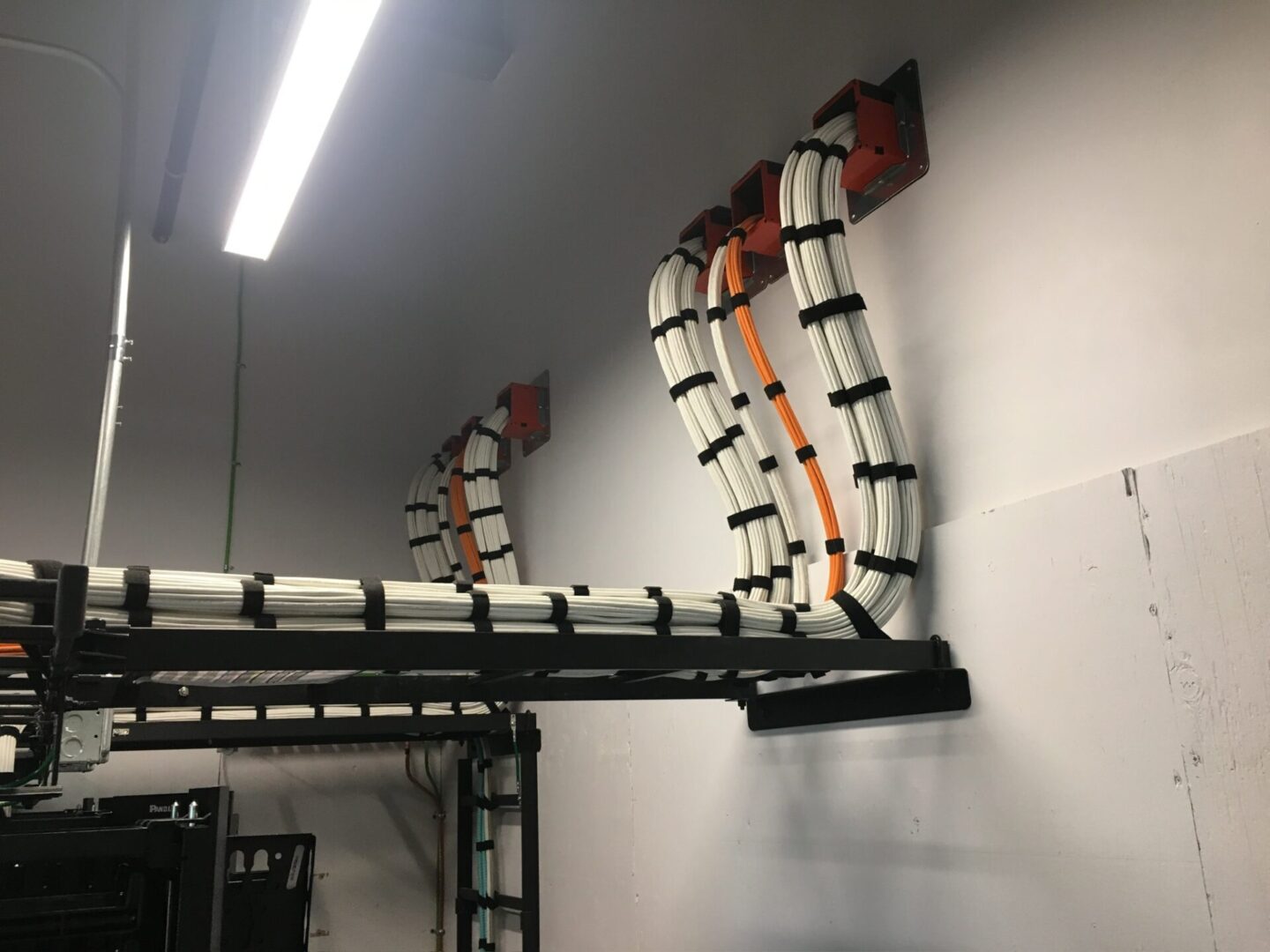 A wall with multiple wires hanging on it.