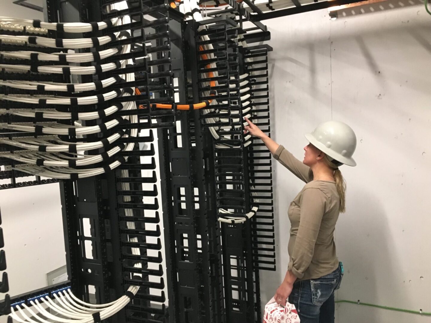 A woman in a hard hat is looking at some racks.