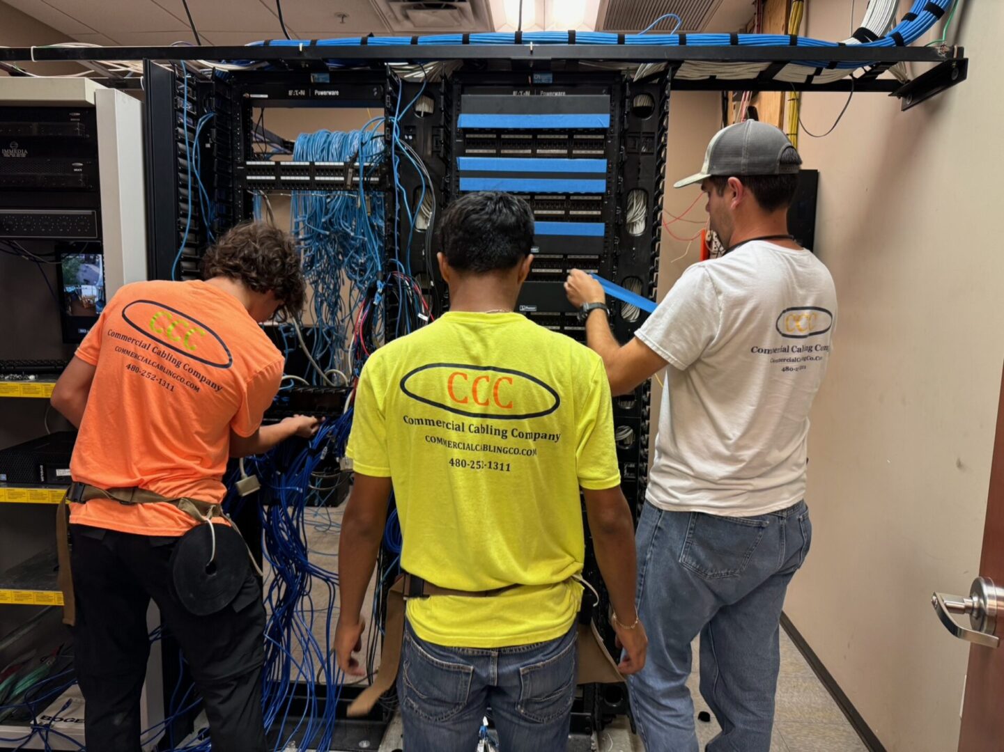 Three men working on a computer system.