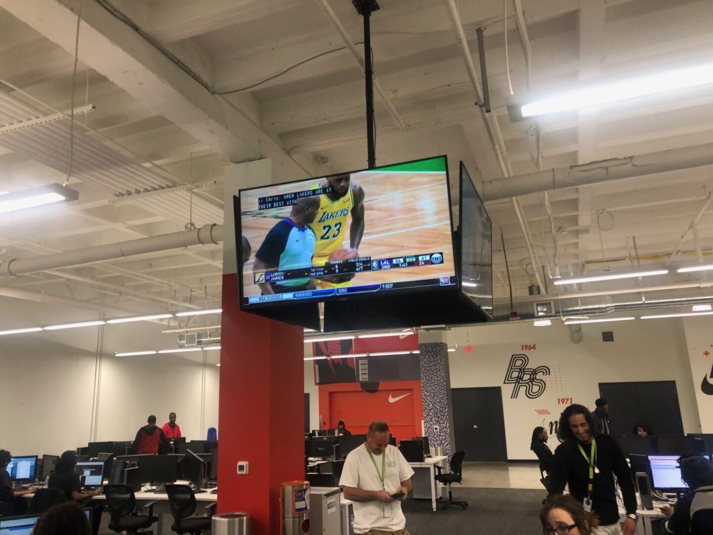 A large tv hanging in the middle of an airport.